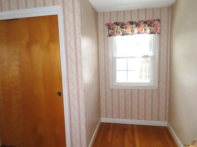 spare room with baseboards, wood finished floors, and wallpapered walls