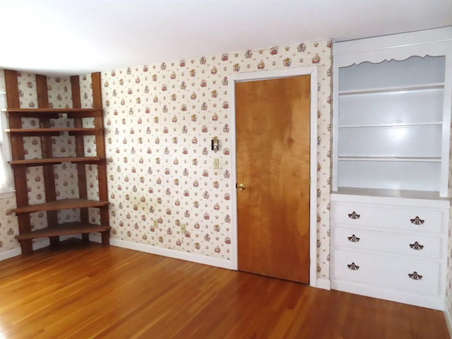 interior space with wood finished floors, baseboards, and wallpapered walls