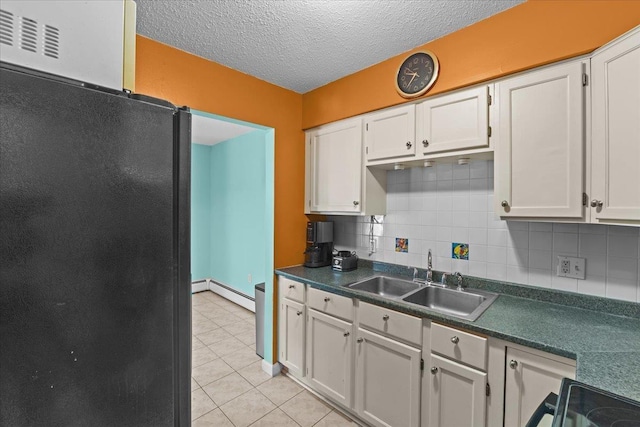 kitchen with a textured ceiling, a baseboard radiator, a sink, backsplash, and dark countertops