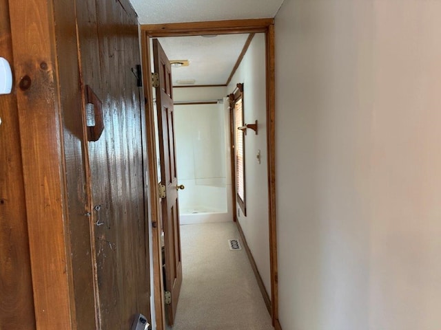 hallway featuring carpet floors, visible vents, and baseboards