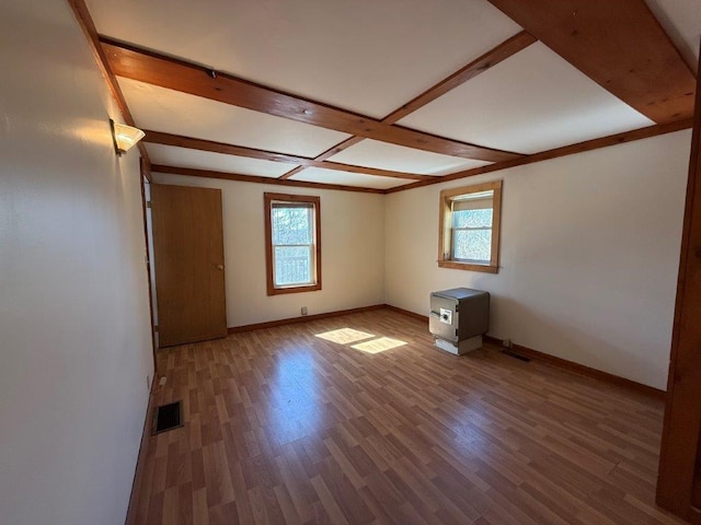 spare room featuring plenty of natural light, wood finished floors, visible vents, and baseboards