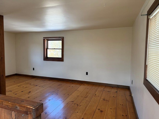 spare room with baseboards and hardwood / wood-style floors