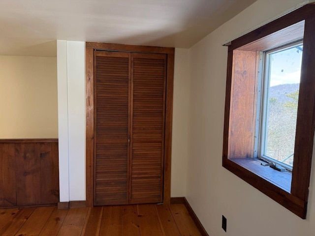 unfurnished bedroom featuring a closet, light wood-type flooring, and baseboards