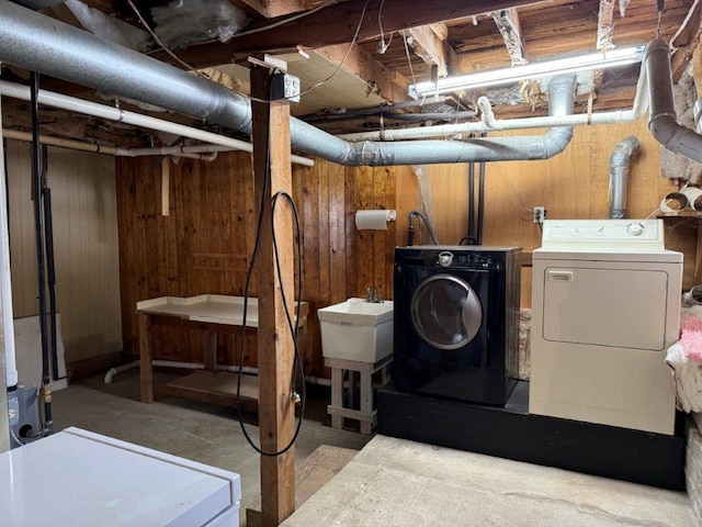 unfinished below grade area featuring wood walls, a sink, and separate washer and dryer