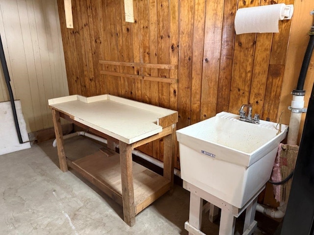 misc room featuring unfinished concrete floors, a sink, and wooden walls