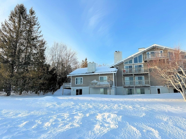 snow covered rear of property featuring a chimney