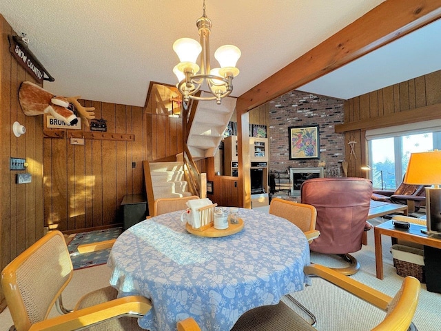 dining room with stairway, carpet flooring, wood walls, a fireplace, and a chandelier