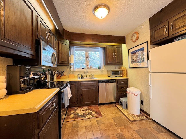 kitchen featuring dark brown cabinets, appliances with stainless steel finishes, light countertops, and a sink