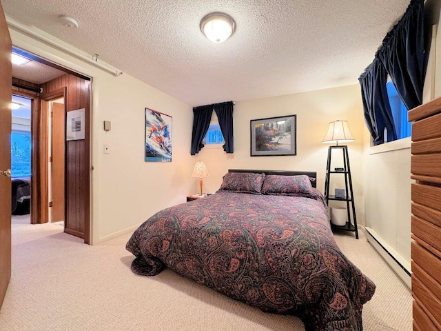 bedroom featuring baseboards, carpet, a baseboard heating unit, and a textured ceiling