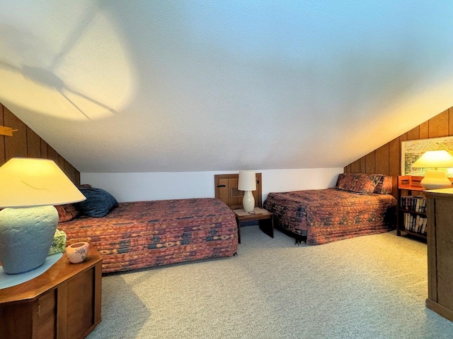 carpeted bedroom featuring a textured ceiling, wood walls, and vaulted ceiling