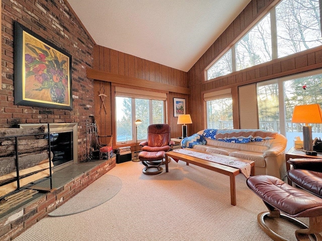 carpeted living room with wooden walls, a fireplace, high vaulted ceiling, and a wealth of natural light