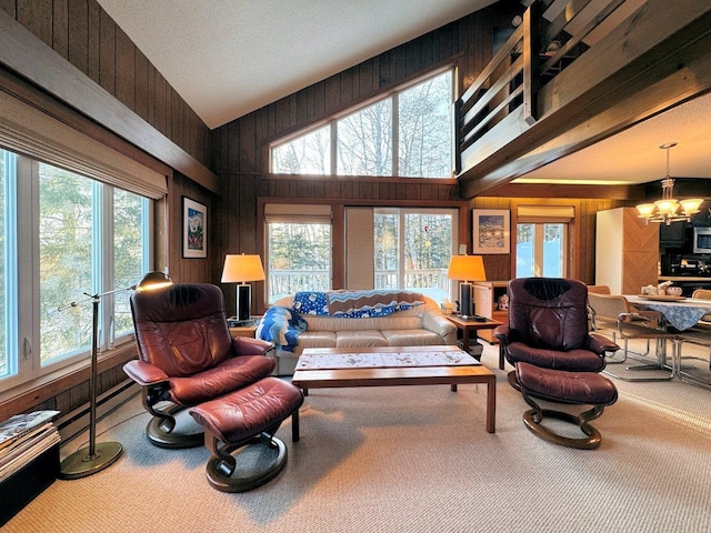 carpeted living room with a high ceiling, wood walls, plenty of natural light, and a notable chandelier