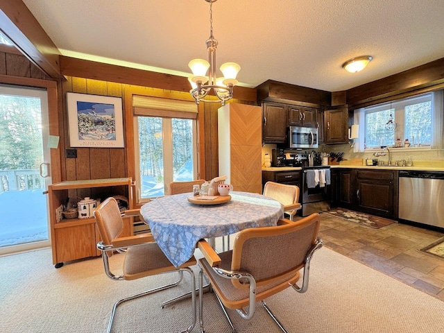 dining area featuring wooden walls, stone finish floor, a notable chandelier, and a textured ceiling