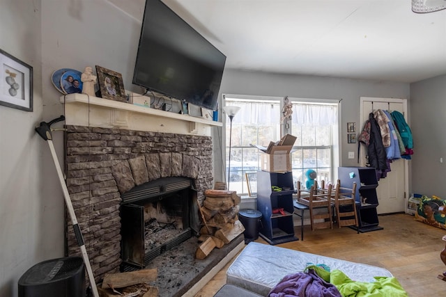 living room with a stone fireplace and wood finished floors