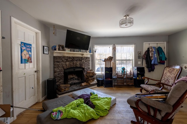 living area featuring hardwood / wood-style floors and a stone fireplace