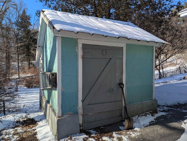 snow covered structure with an outbuilding and a shed