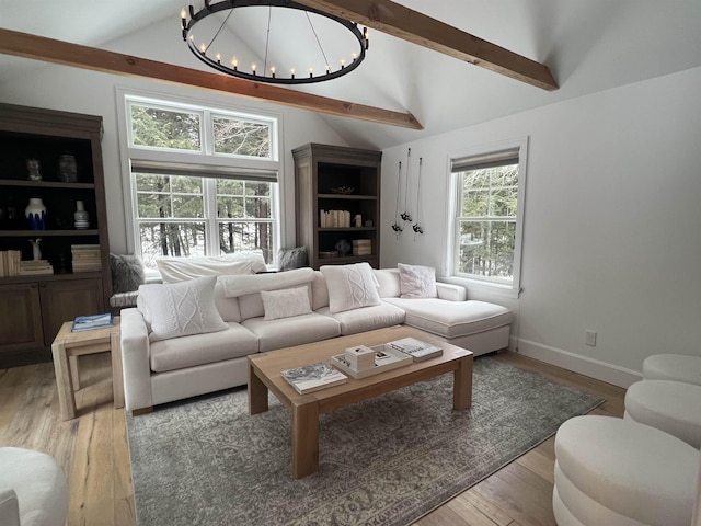 living room featuring a notable chandelier, lofted ceiling with beams, and light wood-style floors