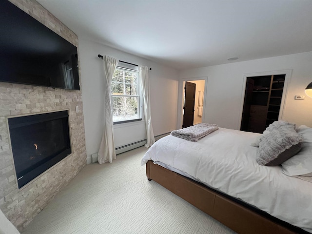 bedroom featuring light carpet, baseboard heating, and a glass covered fireplace