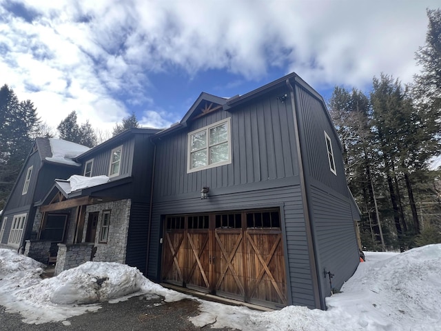 view of front of property with a garage, stone siding, and board and batten siding