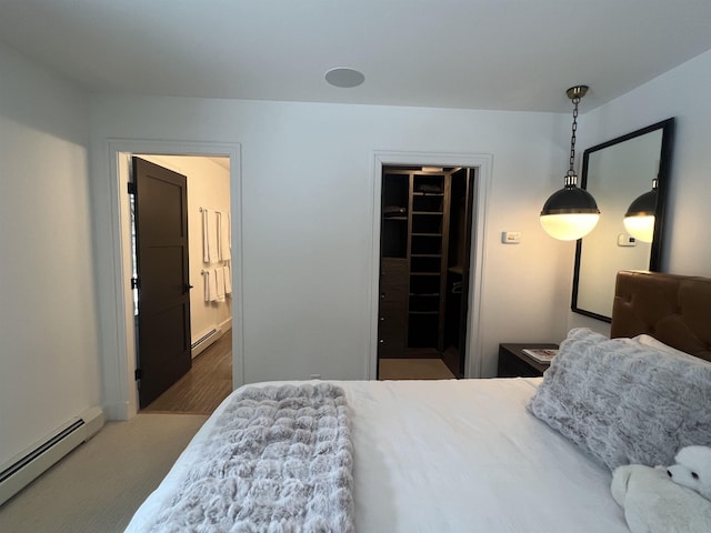 carpeted bedroom featuring a walk in closet, ensuite bathroom, and a baseboard radiator