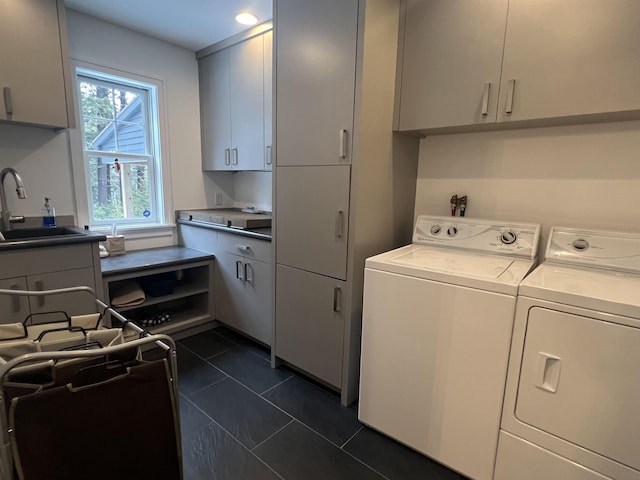 clothes washing area featuring cabinet space, dark tile patterned flooring, separate washer and dryer, and a sink