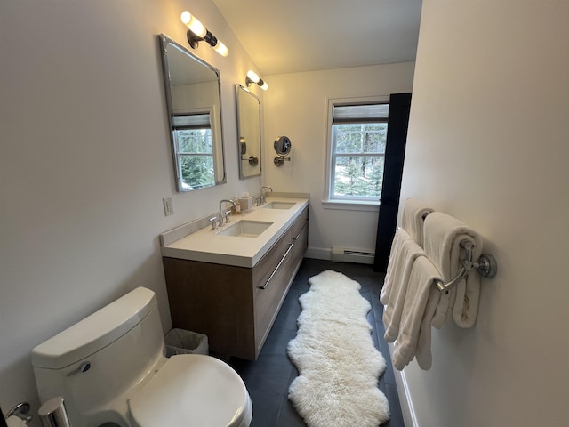 full bathroom with double vanity, a sink, toilet, and a baseboard radiator