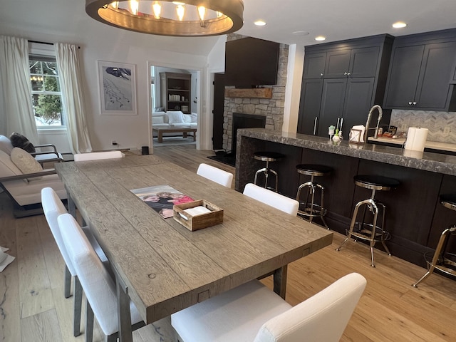 dining area with recessed lighting, light wood-style flooring, and a fireplace