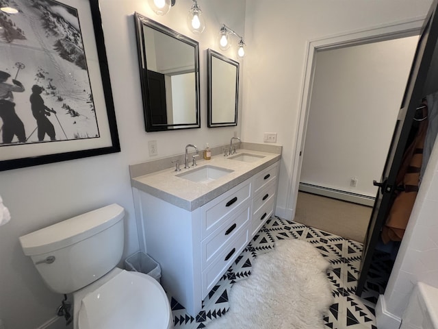 bathroom featuring double vanity, toilet, a baseboard heating unit, and a sink