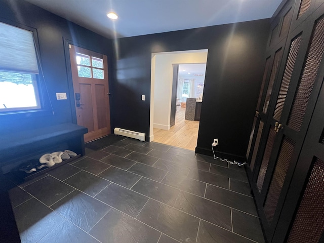 entrance foyer with a baseboard heating unit, baseboards, and dark tile patterned flooring