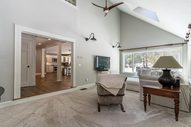 living room with a skylight, baseboards, visible vents, carpet floors, and high vaulted ceiling