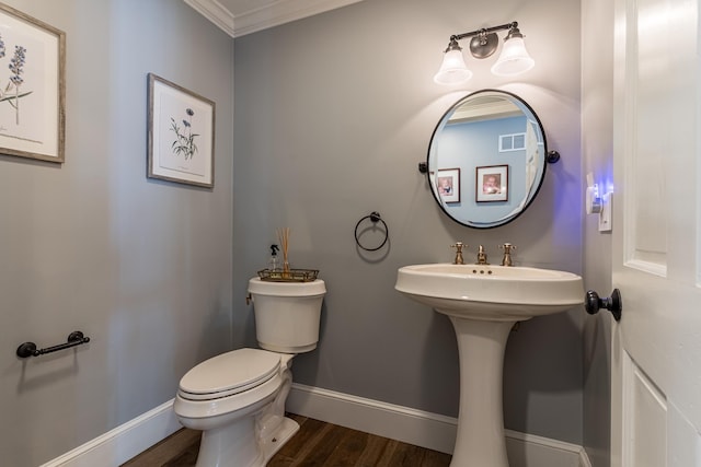 bathroom featuring toilet, wood finished floors, visible vents, baseboards, and crown molding