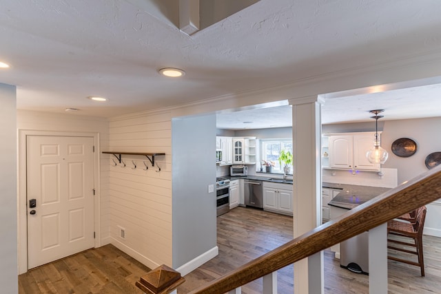 hallway featuring a toaster, wooden walls, a sink, and wood finished floors