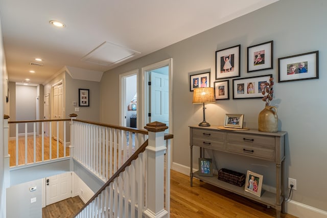 corridor with visible vents, baseboards, an upstairs landing, light wood-type flooring, and attic access