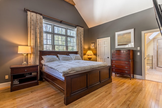 bedroom with high vaulted ceiling, light wood-style floors, baseboards, and connected bathroom