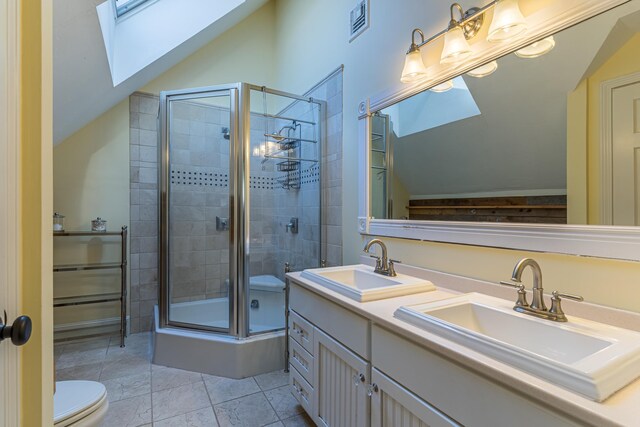 bathroom featuring lofted ceiling with skylight, a sink, a shower stall, and toilet