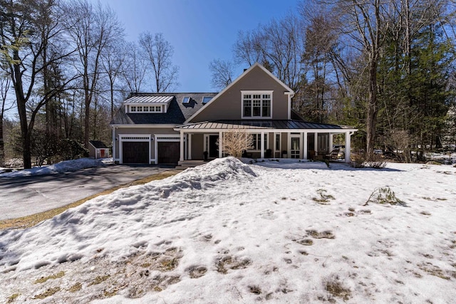 view of front facade with a porch, a standing seam roof, metal roof, and driveway