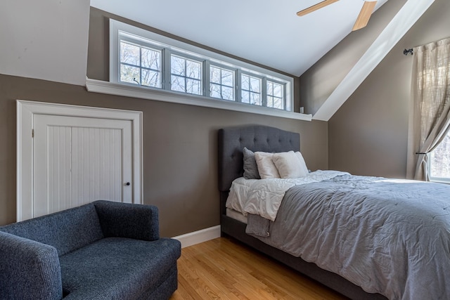 bedroom featuring baseboards, multiple windows, vaulted ceiling, and light wood-style floors