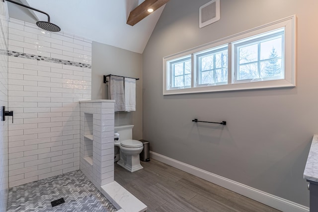 bathroom featuring baseboards, visible vents, toilet, vaulted ceiling with beams, and a tile shower