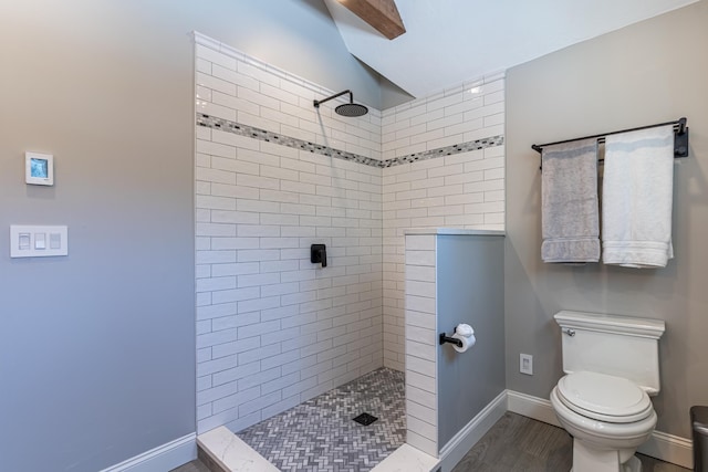 full bath featuring wood finished floors, a tile shower, toilet, and baseboards