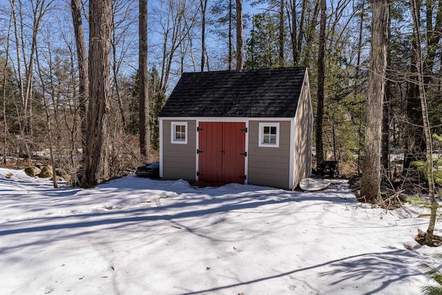 snow covered structure with an outbuilding and a storage shed