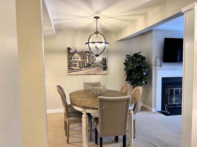 carpeted dining area with baseboards, a fireplace with flush hearth, and a notable chandelier