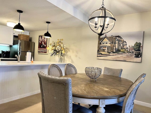 dining space featuring a chandelier, a textured ceiling, carpet, and baseboards