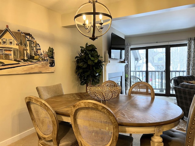 dining space with a chandelier, a fireplace, and baseboards