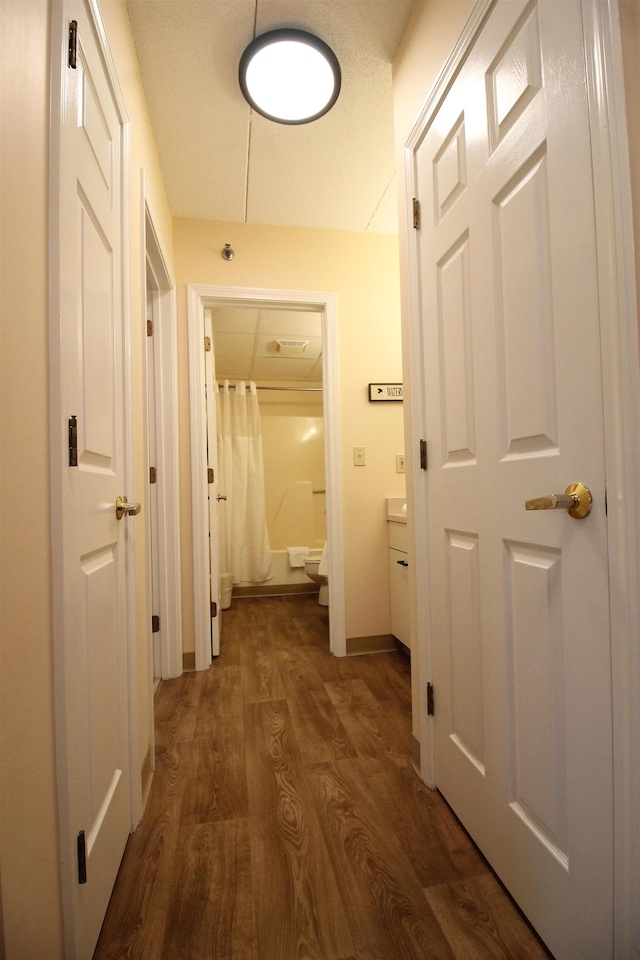 hallway featuring dark wood finished floors and baseboards