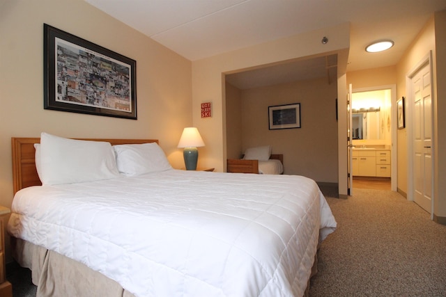 bedroom with light colored carpet, connected bathroom, and baseboards