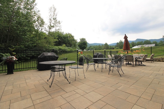 view of patio with outdoor dining area, a grill, a mountain view, and a fenced backyard