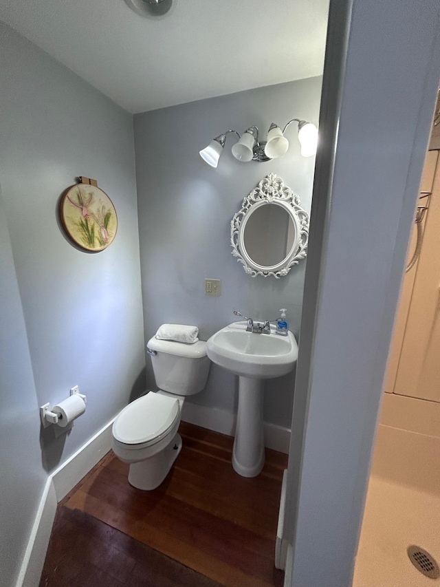 bathroom featuring toilet, a sink, baseboards, and wood finished floors