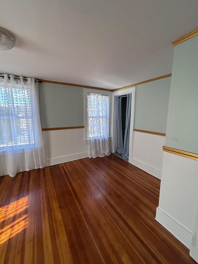 empty room with baseboards, crown molding, and hardwood / wood-style floors