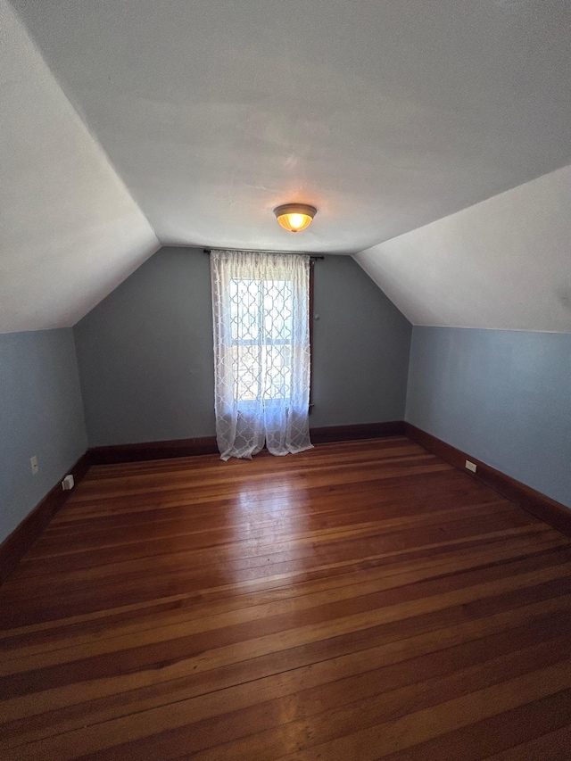 bonus room with lofted ceiling, baseboards, and wood finished floors