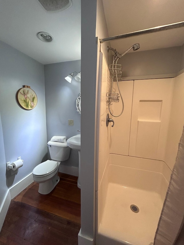 full bathroom featuring toilet, a stall shower, baseboards, and wood finished floors